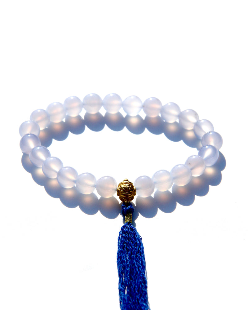 The Healers bracelet, blue chalcedony.  With a 24k gold bead and blue cotton tassel.  Blue chalcedony helps create the Sacred voice. It also has strong color healing abilities.  Stretch bracelet. Length: 18 cms.