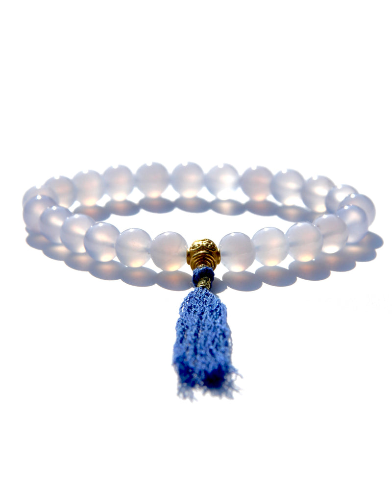 The Healers bracelet, blue chalcedony.  With a 24k gold bead and blue cotton tassel.  Blue chalcedony helps create the Sacred voice. It also has strong color healing abilities.  Stretch bracelet. Length: 18 cms.