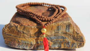 Rudraksha beads mala necklace with a 24k gold bead.  It is written on the gold bead: Om Mani Padme Om.  This is stage 2 of Rudhraksha beads ' growth. The Rudraksha beads in the minis collection are smoother and the clear separation lines have not appeared yet..  It is being said that wearing a Rudraksha beads mala cancels your karma!