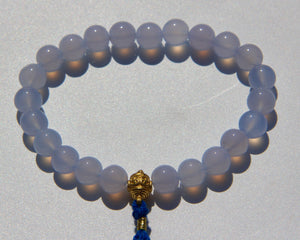 The Healers bracelet, blue chalcedony.  With a 24k gold bead and blue cotton tassel.  Blue chalcedony helps create the Sacred voice. It also has strong color healing abilities.  Stretch bracelet. Length: 18 cms.