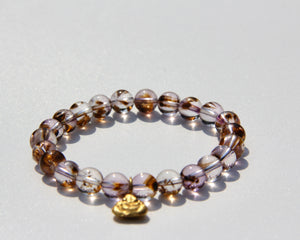 Stretch bracelet, beads made of Cacoxenite Amethyst.   Each beads has wisps of golden cacoxenite. The beads are crystal clear and full of Light. This is truly a magnificent strandSmall 18k gold laughing Buddha.